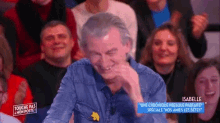 a man is laughing in front of a crowd while wearing a blue shirt