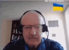 a man wearing glasses and headphones looks at the camera while talking on a video call .
