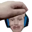 a hand is holding a person 's head with headphones on .