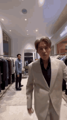 a man in a suit is walking through a store with clothes on display