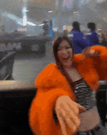 a blurred image of a woman in an orange jacket