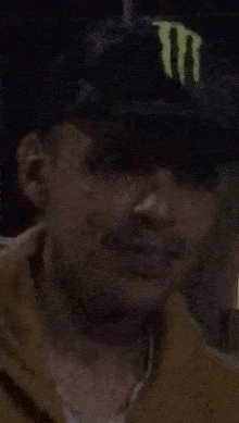 a man with a beard is wearing a hat and a brown jacket .