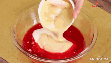 a person is pouring a liquid into a glass bowl with the words made in animatica on the bottom