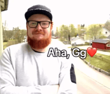 a man with a beard wearing glasses and a hat with aha gg written on his shirt