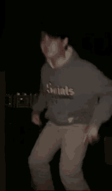 a person in a gray sweatshirt is dancing in the dark .