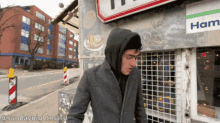a man in a hooded jacket is standing in front of a ham shop