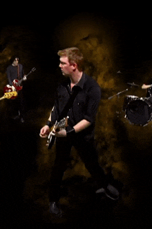 a man in a black shirt is playing a guitar in a band