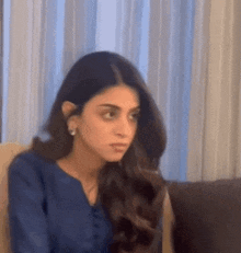 a woman in a blue shirt is sitting on a couch .