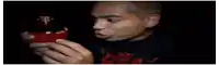 a man is smelling a red liquid in a bottle .