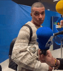 a man wearing a sweater is being interviewed by a reporter