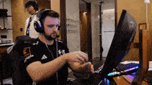 a man wearing headphones sits at a desk with a monitor that says gigabyte on it