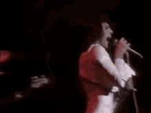 a man in a white shirt is singing into a microphone on a stage .