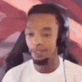 a man wearing headphones and a white shirt is sitting in front of a computer screen .