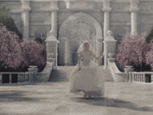 a woman in a white dress is dancing in front of a building