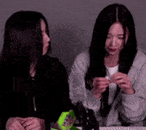 two women are sitting next to each other and one of them is holding a green bag that says ' ire ' on it