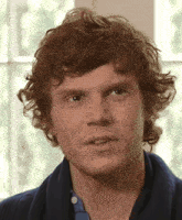 a close up of a man 's face with red curly hair