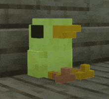 a green block with a yellow beak sits on a wooden surface
