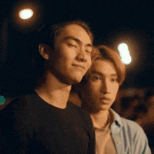 two young men are standing next to each other at night with their eyes closed