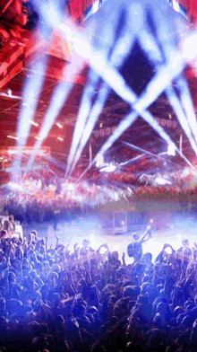 a crowd of people at a concert with blue and red lights coming out of the ceiling