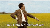 a man in a suit and tie is standing in a field with his arms outstretched and waiting on ferguson .