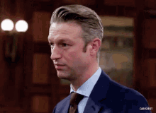 a man in a suit and tie is standing in a room with the words carisibot below him