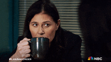 a woman drinking a cup of coffee with the nbc logo in the corner