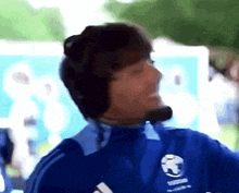 a man wearing headphones and a blue shirt with a soccer ball on it is smiling .