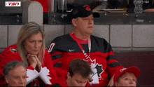 a man wearing a canada jersey sits in the stands with a woman