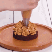 a person is frosting a brownie on a wooden plate with easy plus written on the bottom