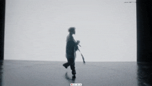 a silhouette of a person walking in front of a white wall with a red live button