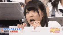 a girl is sitting in a stadium with her mouth open and looking at something .