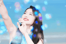a woman in a blue dress is smiling with bubbles coming out of her hands