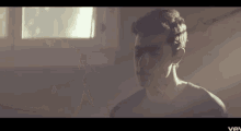 a close up of a man 's face in front of a window in a room .