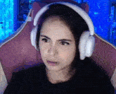 a woman wearing headphones is sitting in a pink chair and making a funny face .