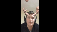 a young man wearing headphones has a doll 's head on his head