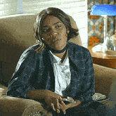 a woman in a plaid shirt and choker sits on a couch