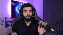 a man with a beard is wearing headphones and holding a microphone in front of him