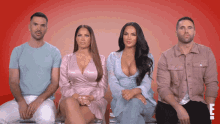 a group of people sitting in front of a red background with the letter u on the bottom right
