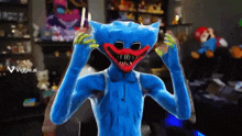 a blue monster is standing in a room with a viggle.ai logo on the bottom right