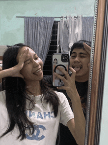 a man and a woman are taking a selfie in a mirror