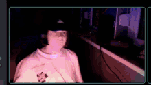 a man wearing a hat and headphones is sitting in front of a computer screen