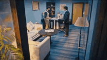 two men are standing in a room with a couch and a table .