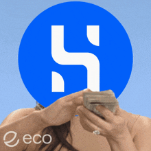 a woman holding a pile of money in front of a blue circle with the letter h on it