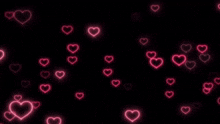 a bunch of neon hearts are floating in the air on a black background