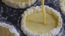 a close up of a person pouring liquid into a pastry crust