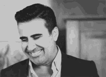 a black and white photo of a man in a suit smiling