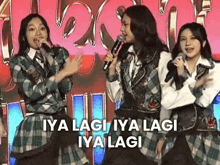 a group of girls are singing into microphones while standing next to each other on a stage .