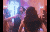 a woman in a black dress is dancing in a room with other women .