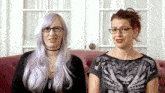 two women are sitting next to each other on a couch and one has glasses on