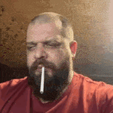 a bald man with a beard is smoking a cigarette .